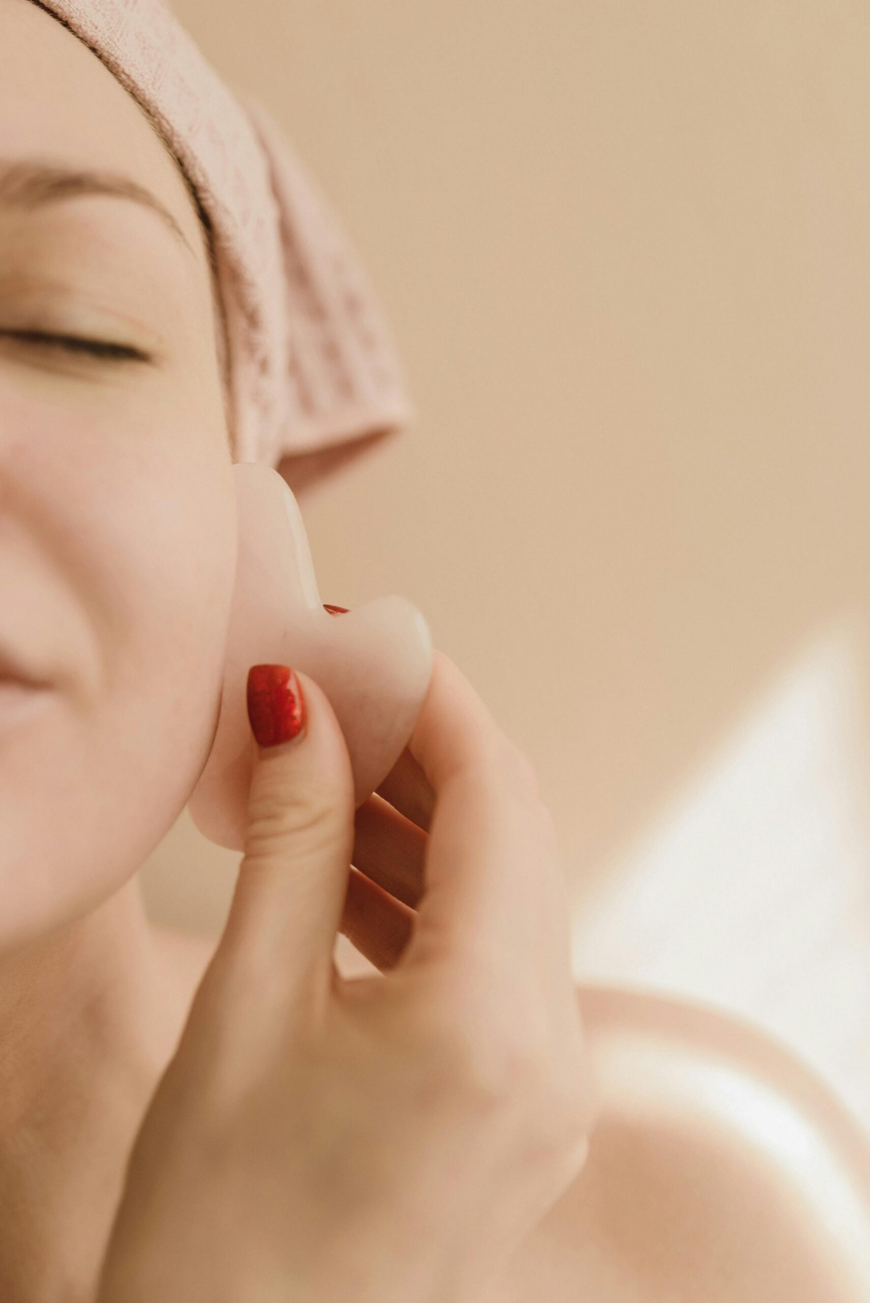 Close-up of woman using a gua sha tool for a calming skin massage routine.